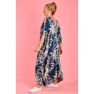 Introducing the Cushla Dress, a stunning Kaftan maxi dress in a timeless Navy hue featuring a charming palm Tree print with cream tones. This dress boasts unique button details on the shoulder and arm, creating stylish openings that enhance its batwing sleeves for a flowing design. 