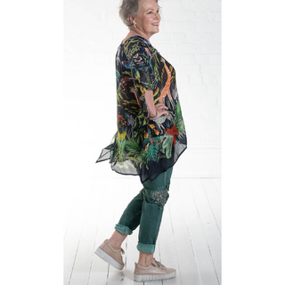 100% Silk Kaftan in a One Size fit. The black background provides a striking contrast to the vibrant jungle and foliage design, which features an array of lush green leaves, exotic flowers, and colorful animals. The design is bold and eye-catching, creating a tropical and exotic vibe.