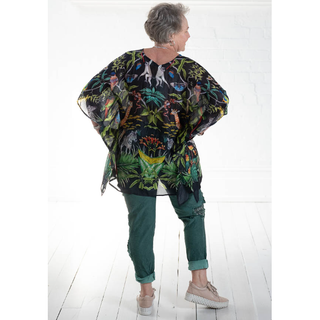 100% Silk Kaftan in a One Size fit. The black background provides a striking contrast to the vibrant jungle and foliage design, which features an array of lush green leaves, exotic flowers, and colorful animals. The design is bold and eye-catching, creating a tropical and exotic vibe.